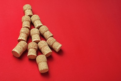 Christmas tree made of wine corks on red background. Space for text