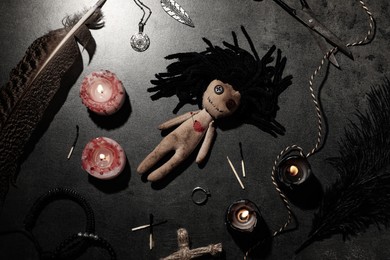 Female voodoo doll with pin in heart and ceremonial items on grey table, flat lay