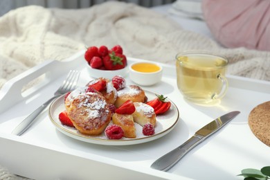 Tasty breakfast served in bedroom. Cottage cheese pancakes with fresh berries and icing sugar on wooden tray