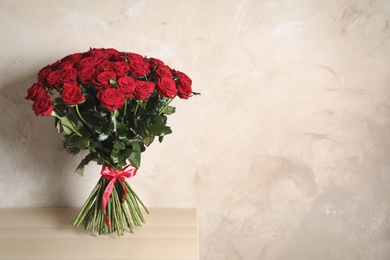 Luxury bouquet of fresh red roses on wooden table, space for text