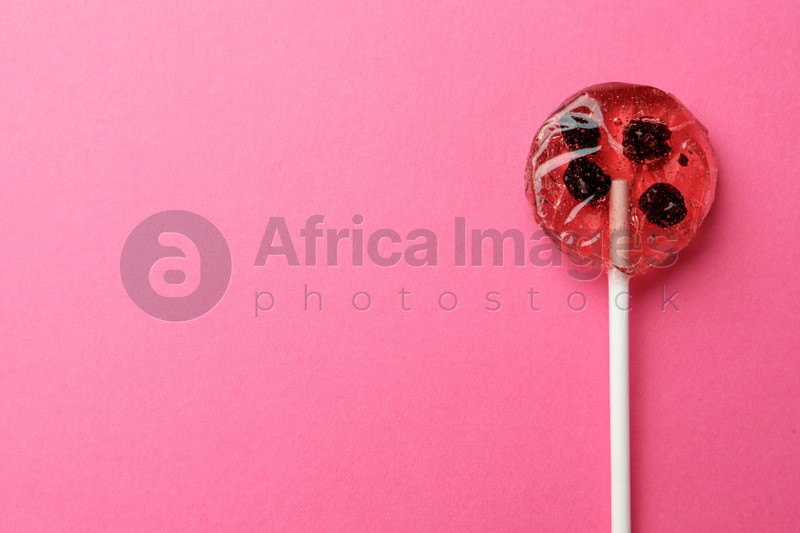 Sweet colorful lollipop with berries on pink background, top view. Space for text