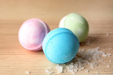Photo of Colorful bath bombs and cosmetic salt on wooden background