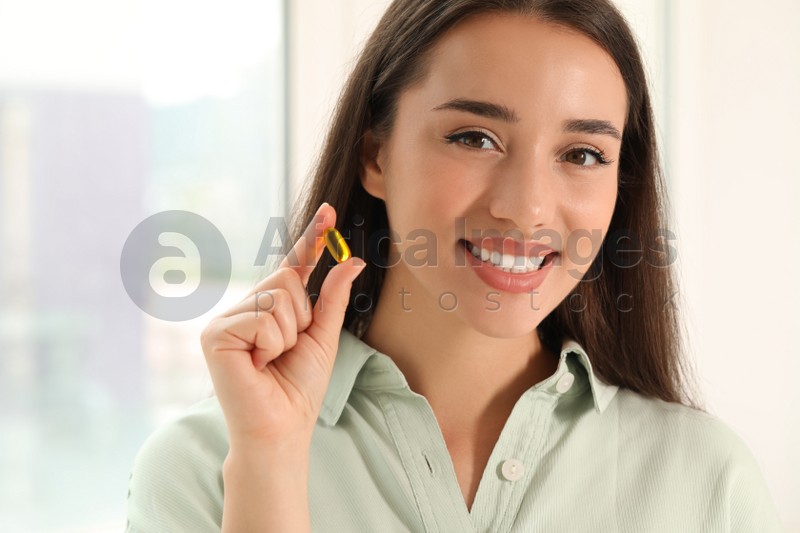 Young woman with dietary supplement pill indoors