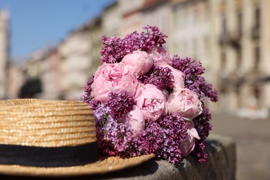 Photo of Bouquet of beautiful spring flowers and straw hat outdoors