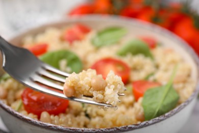 Fork with delicious quinoa salad, closeup view