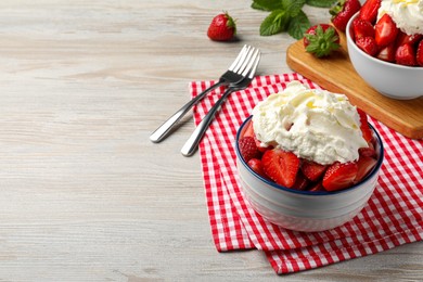 Delicious strawberries with whipped cream served on wooden table, space for text