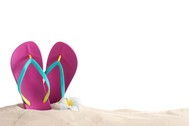 Photo of Pink flip flops and plumeria flower on sand against white background, space for text. Beach objects