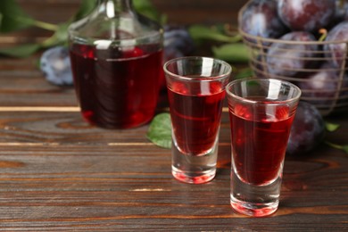 Photo of Delicious plum liquor on wooden table. Homemade strong alcoholic beverage