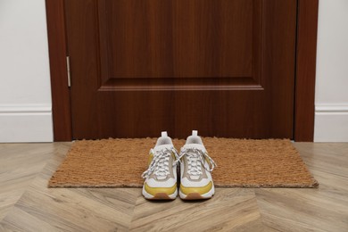 Stylish shoes near door mat in hall