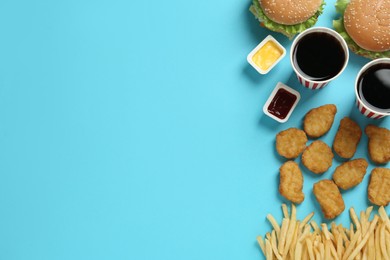 Flat lay composition with delicious fast food menu on light blue background. Space for text