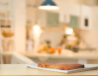 Towel and cutting board on wooden table in kitchen. Space for text