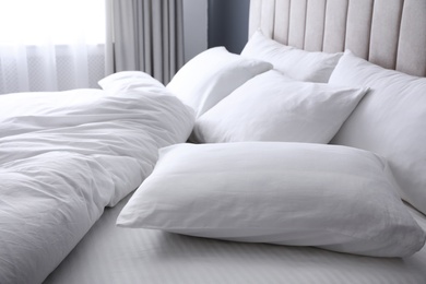 Photo of Comfortable bed with soft white pillows, closeup