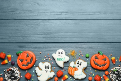 Tasty cookies and sweets for Halloween party on blue wooden table, flat lay. Space for text