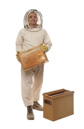 Beekeeper in uniform holding frame with honeycomb near wooden hive on white background