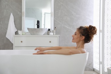 Beautiful woman relaxing in bathtub at home