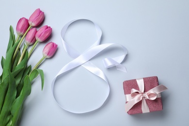 8 March greeting card design with tulips, ribbon and gift box on light grey background, flat lay. International Women's day