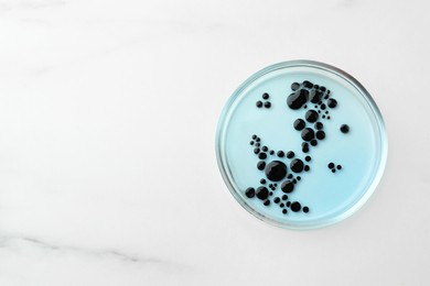 Photo of Petri dish with culture on white marble table, top view. Space for text