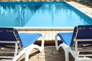 Photo of Comfortable loungers at clean swimming pool on sunny day