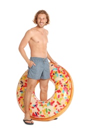 Attractive young man in swimwear with doughnut inflatable ring on white background