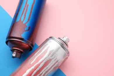 Used cans of spray paints on color background, above view with space for text. Graffiti supplies
