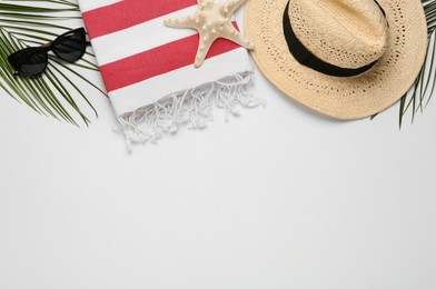Beach towel, straw hat and sunglasses on light background, flat lay. Space for text
