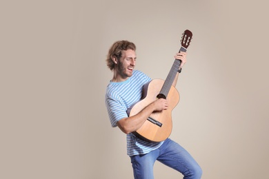 Young man playing acoustic guitar on grey background. Space for text