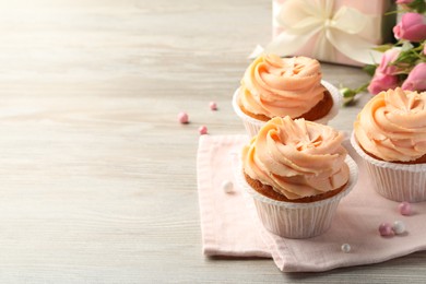 Photo of Tasty cupcakes with cream on wooden table, space for text