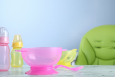 Plastic bowl and spoon on white marble table indoors, space for text. Serving baby food