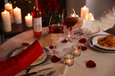 Couple clinking glasses of wine indoors, closeup. Romantic dinner