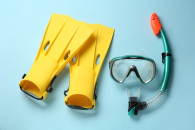 Pair of yellow flippers and mask on light blue background, flat lay