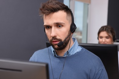 Photo of Handsome call center operator with headset working in modern office