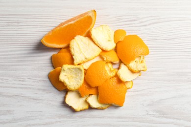 Photo of Orange peels preparing for drying and piece of fresh fruit on white wooden table, flat lay