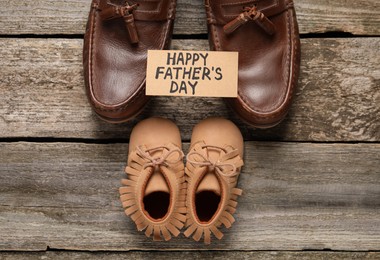 HAPPY FATHER'S DAY. Dad and son's shoes on wooden background, flat lay