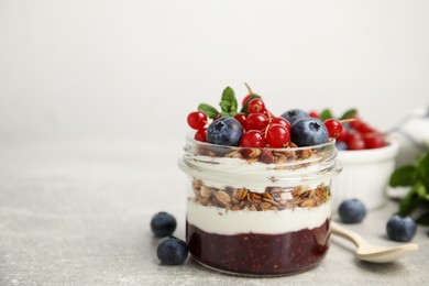 Delicious yogurt parfait with fresh berries and mint on light grey table, space for text