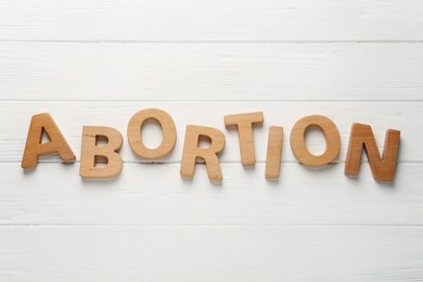 Word Abortion made of letters on white wooden background, flat lay