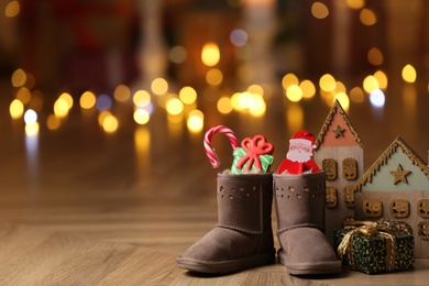 Boots filled with sweets and gift on floor in room, space for text. Saint Nicholas Day