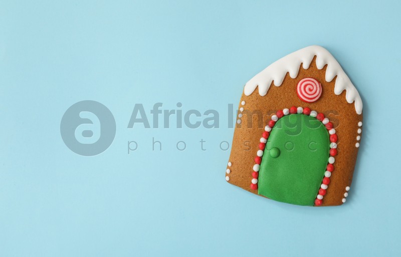 Christmas house shaped gingerbread cookie on light blue background, top view. Space for text