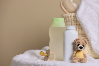 Photo of Baby cosmetic products, toy bear and pacifier on beige background. Space for text