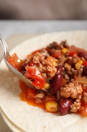 Tasty chili con carne with tortillas on table, closeup