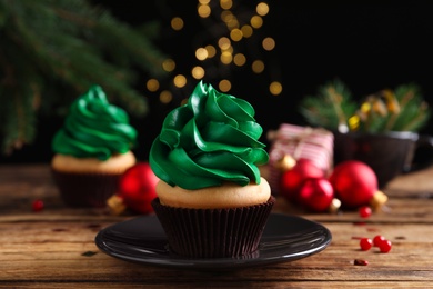 Delicious cupcake with green cream and Christmas decor on wooden table