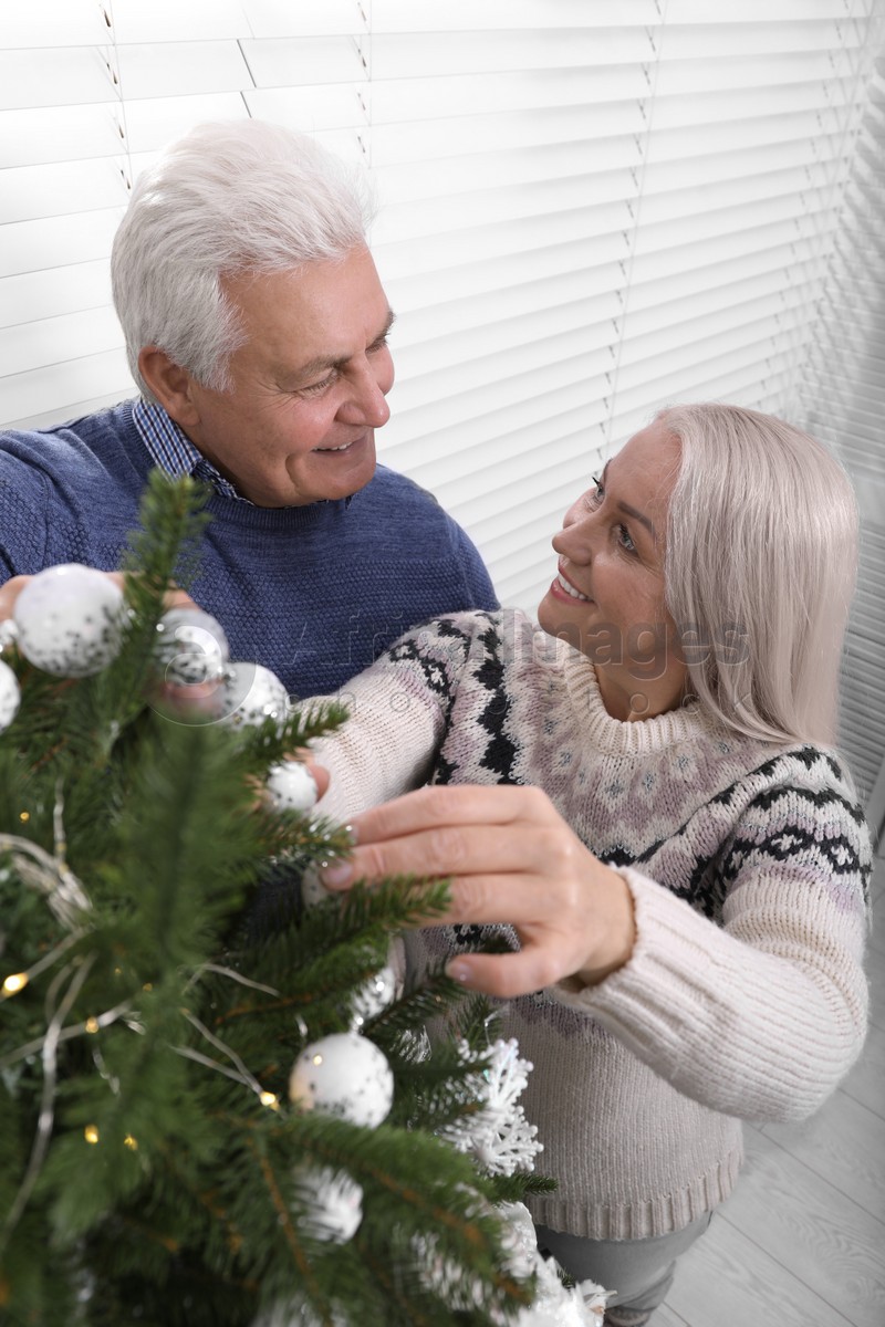 Happy mature couple decorating Christmas tree at home, above view