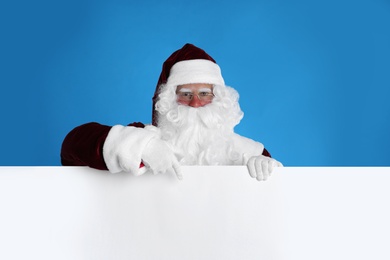Santa Claus holding empty banner on light blue background