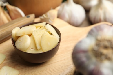 Fresh sliced garlic cloves in bowl on wooden table, closeup. Organic product