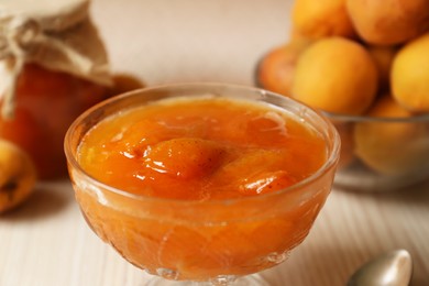 Photo of Dessert bowl with delicious apricot jam on white wooden table, closeup