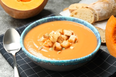Tasty creamy pumpkin soup with croutons and seeds in bowl on table