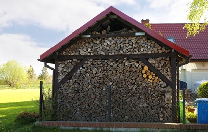 Photo of Shed with stacked firewood outdoors on sunny day
