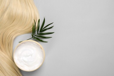 Lock of healthy blond hair, cosmetic product and green twig on light grey background, flat lay. Space for text