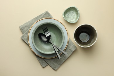 Stylish empty dishware and cutlery on beige background, flat lay