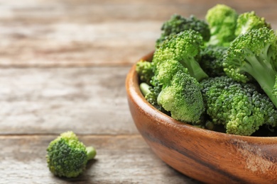 Bowl with fresh green broccoli on wooden table