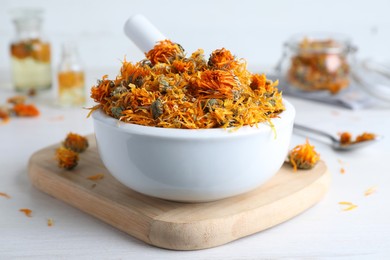 Mortar of dry calendula flowers on white table